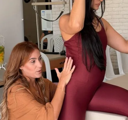 Carol corrigindo a postura de uma aluna